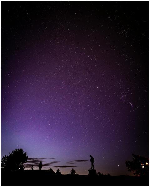 A lone silhouette stands under a vast, starry nigh
