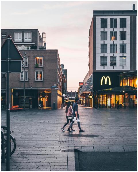 Couple walking in a city square with buildings and