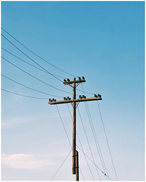 Electrical pole with power lines under a clear blu