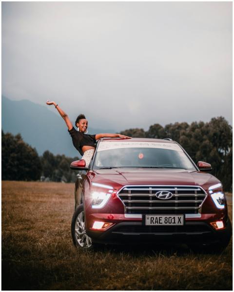 A joyful woman poses with a red Hyundai car in a s