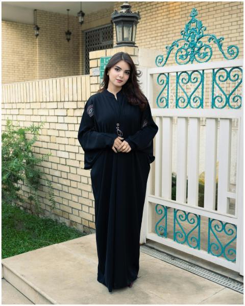 A young woman in traditional clothing poses by a d
