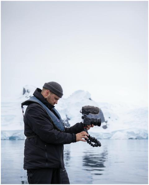 A photographer adjusts his camera amidst snowy arc