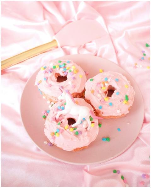 Three pink frosted donuts with colorful sprinkles