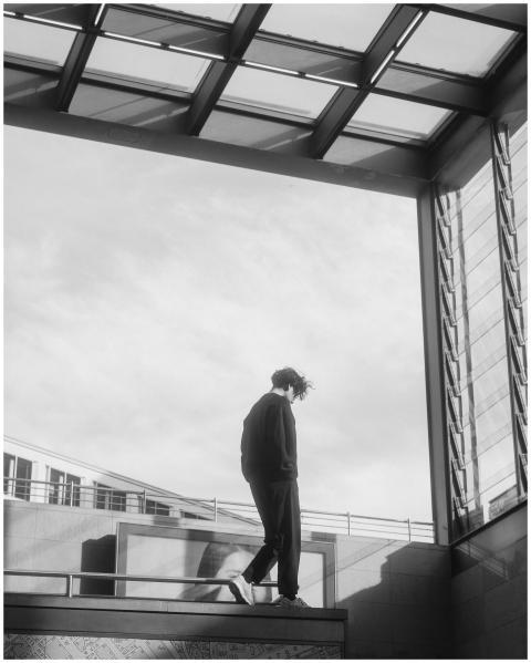 A man in black clothes walks in an urban setting u