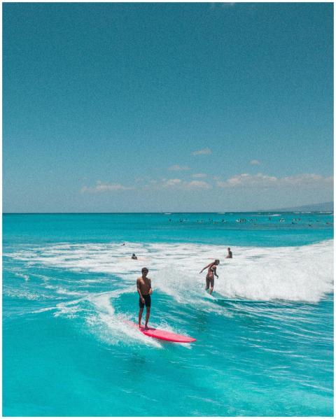 Surfers riding vibrant blue waves in Hawaii, captu