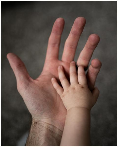 Close-up of a father's hand gently holding his bab