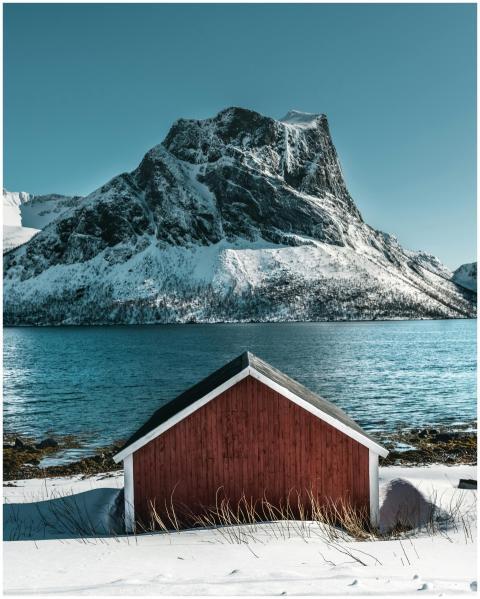 A serene winter landscape featuring a red cabin by