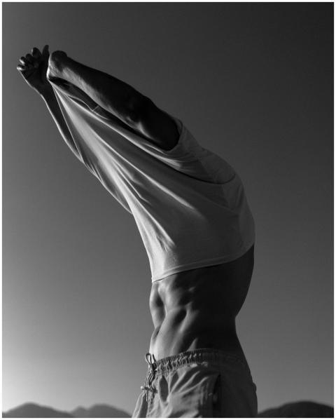 Black and white photo of a muscular man undressing