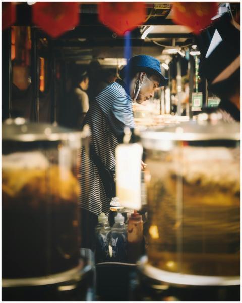 A focused street vendor preparing food in a vibran