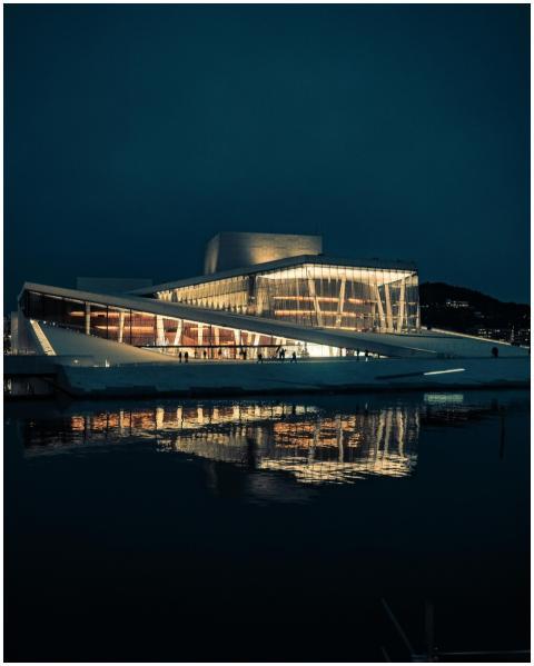 The striking Oslo Opera House glows warmly, reflec