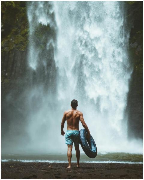 A man enjoying the natural beauty of a waterfall i