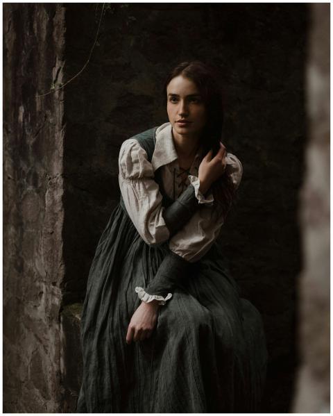 A contemplative woman in a medieval-style dress po