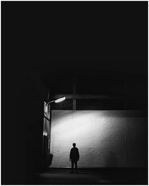 Silhouette of a person under a street lamp in an e