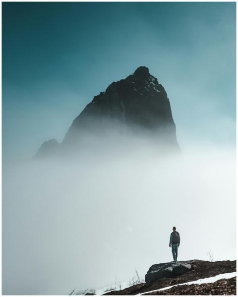 Man stands on rocky terrain surrounded by dense fo