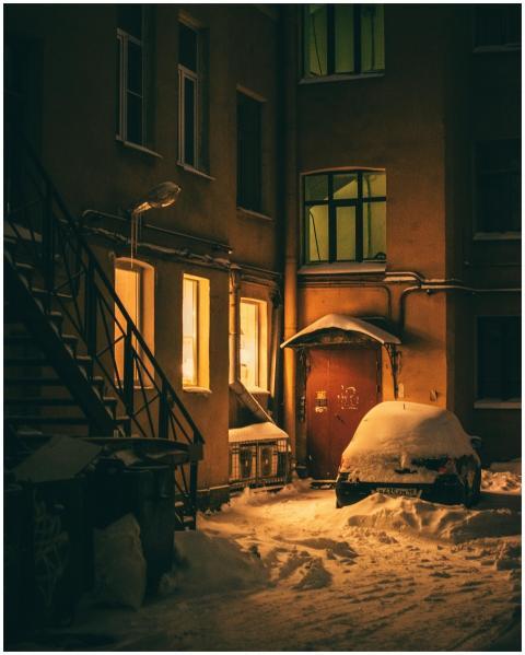 A cozy, snow-covered courtyard with lit windows on