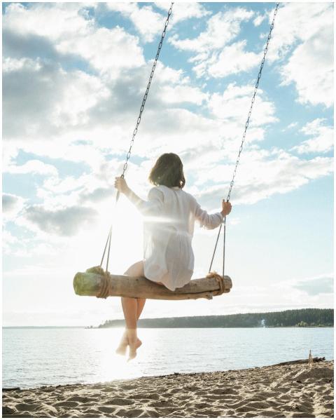 Woman enjoys a peaceful moment on a beach swing wi