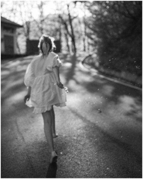 A stylish woman in a white dress walking on a sunn