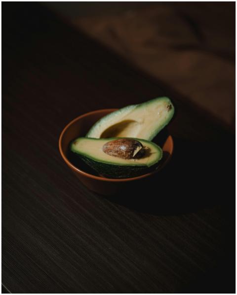 A close-up of a fresh avocado split in a wooden bo