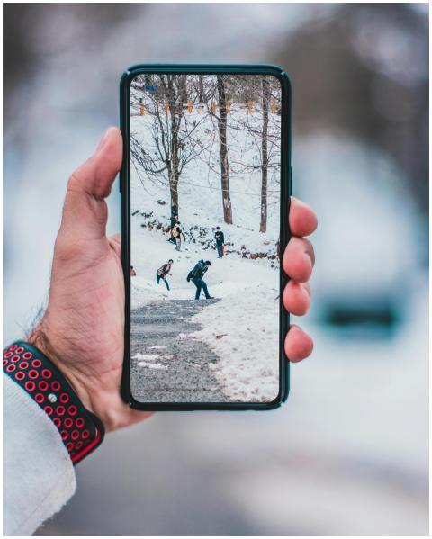 Hand holding smartphone displaying a winter scene