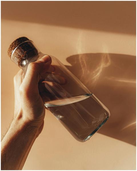 Crop anonymous male holding transparent glass bott