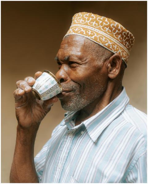 An elderly man savoring tea in traditional attire
