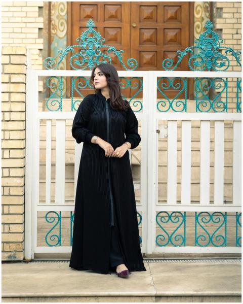 Woman in an elegant black abaya stands by a decora