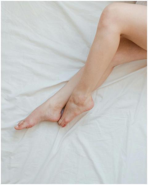 Close-up of relaxed female feet on soft white bed