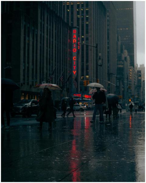 People walking with umbrellas in rain near Radio C