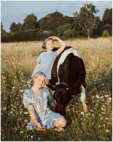 Mother and daughter enjoy a sunny day with a cow i