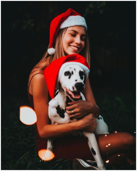 A joyful woman hugging her Dalmatian dog, both wea