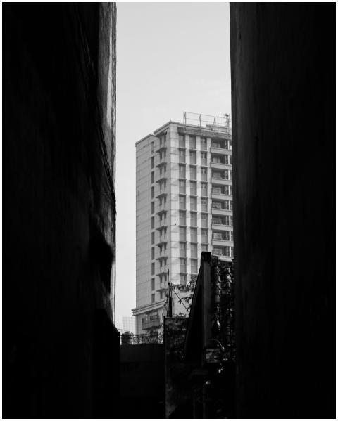 A tall building viewed through a narrow alleyway i
