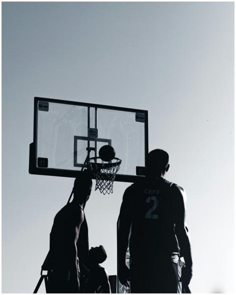 Silhouettes of male basketball players practicing