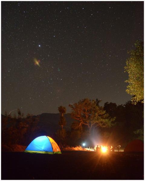 Outdoor camping under a starry night sky with a gl