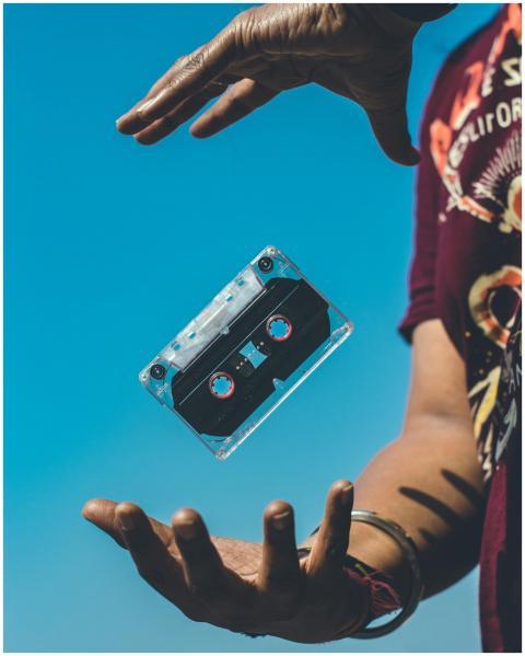 A retro cassette tape floating between hands again