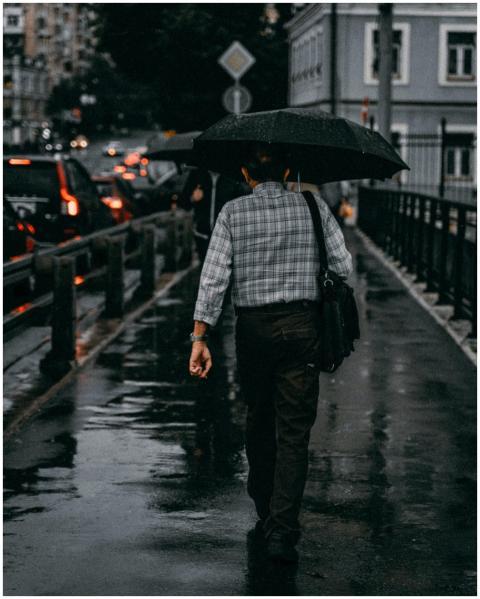 A person walks on a rainy city street, holding an