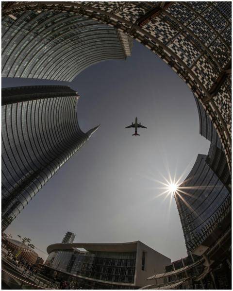 Futuristic cityscape of Milan with an airplane fly