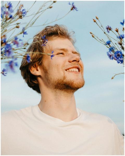 A smiling man in a white t-shirt enjoys a sunny da