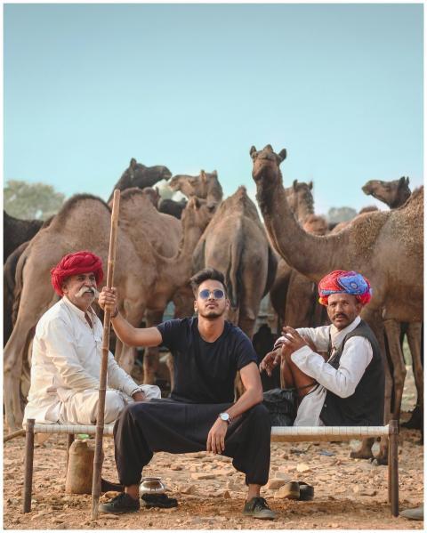 A group of three men sitting with camels in a dese