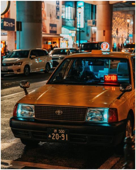 Illuminated taxi on a bustling street in Dotonbori