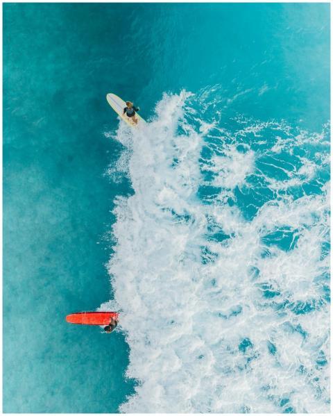 Two surfers catch waves in clear blue waters from