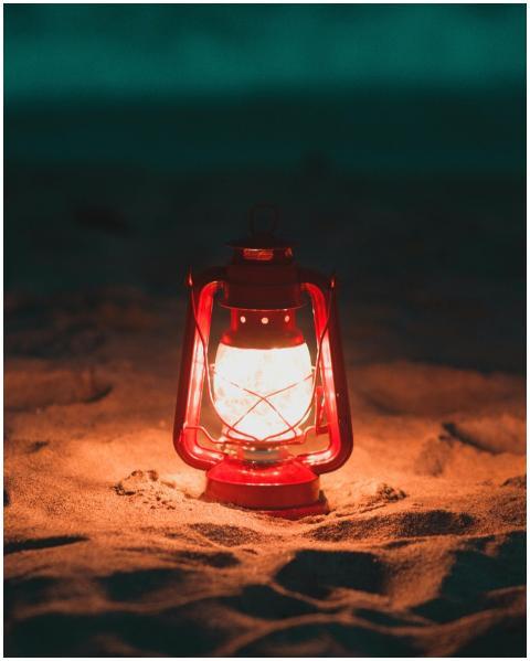 A glowing red lantern lights up the sandy beach du