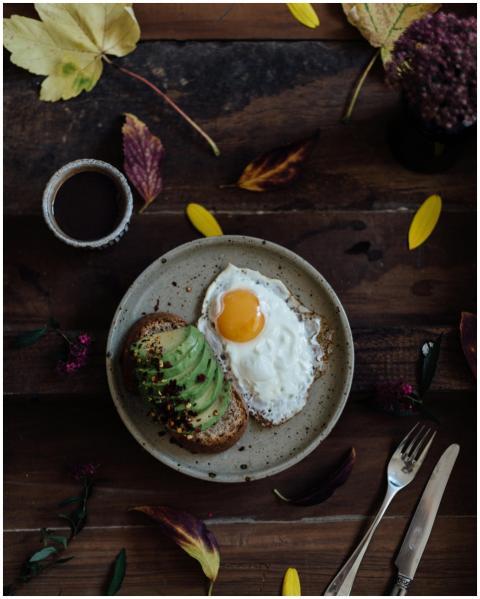 Top view of avocado toast with fried eggs and mug