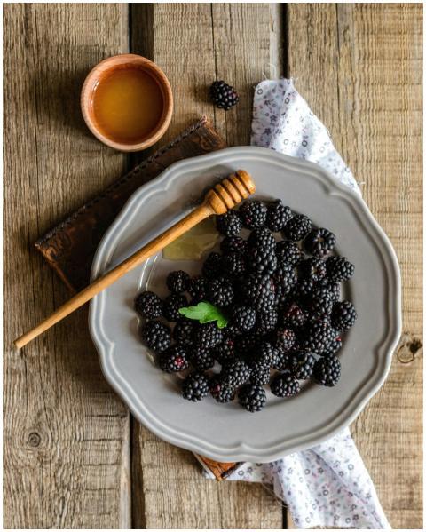 Rustic plate of fresh blackberries served with hon