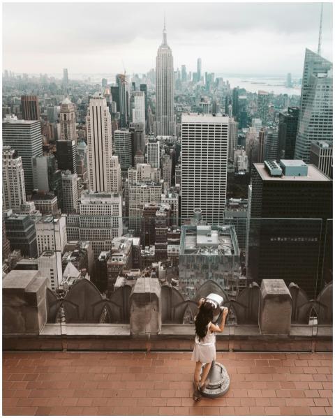A woman using binoculars to view the iconic New Yo