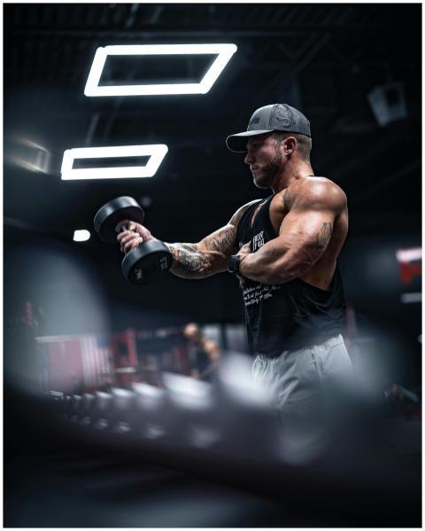 A muscular man in sportswear lifting dumbbells ind