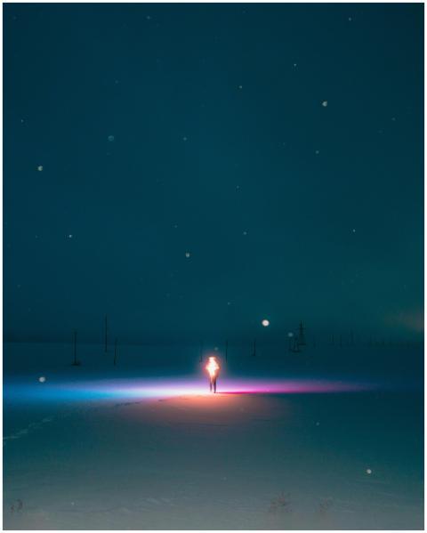 A person standing amidst colorful lights on a snow