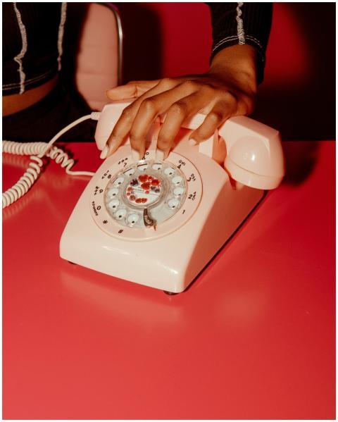 A close-up of a hand on a vintage pink rotary phon
