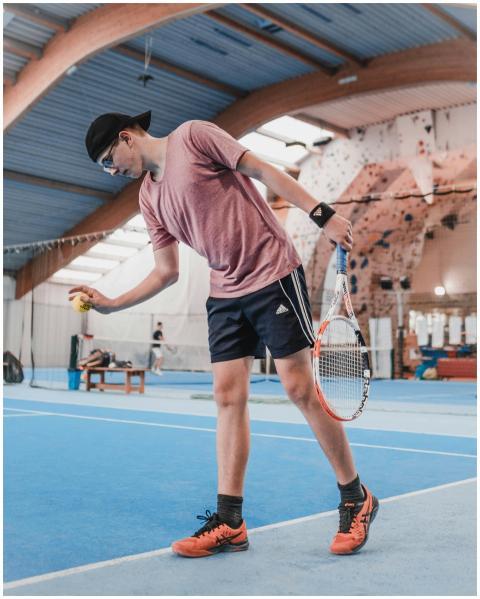 Young athlete preparing to serve on an indoor tenn