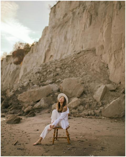 Woman in white sitting on a chair by cliffs at the