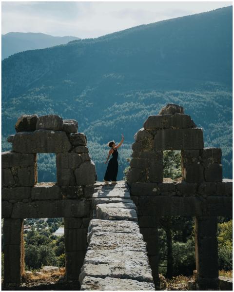 A woman poses gracefully on an ancient stone struc